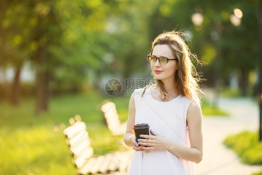 脸户外部美丽的城市女孩肖像手拿着纸杯快乐笑的女人在市公园走着时装金发美女戴着眼镜的美丽金发女孩图片