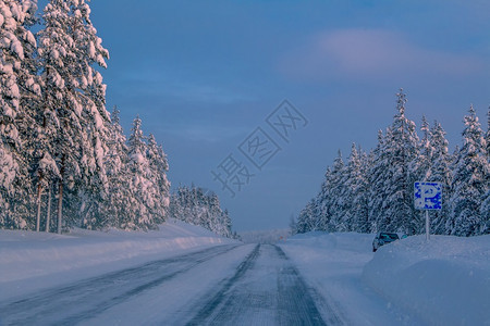 云冬季高速公路穿过雪林和一辆单车在停场渡过寒冷的森林晚上好芬兰白雪斯普鲁树就在阳光之的粉红Rays路边停車處白雪皑图片
