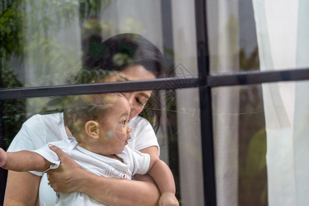 视窗亚洲幸福家庭一幕母亲背着男孩在房子窗户旁边的亚洲幸福家庭场景生活方式概念曼谷屋图片