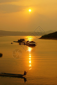 美丽黄色的日出落时越南农村摘要黄天上的阳光充满活力的颜色在越南DakakNamKa湖越南DakakKakk水上房屋划一排船的人轮图片