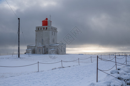 旅游Dyrholaey角灯塔全景图像冰雪和清晨光照冰岛冬季环境风景优美图片