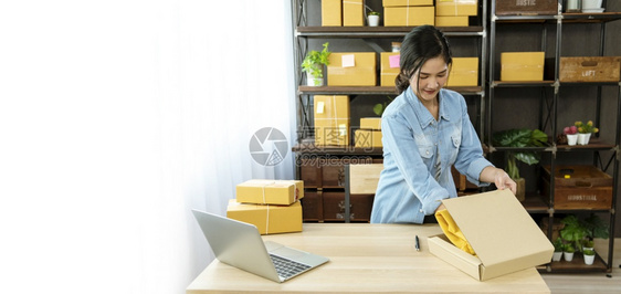 表格上的妇女包装箱检查向亚洲女客户的妇托运货物包装交付物的情况在主办公台服务开小企业家将产品包装成送货文档电子商务为了图片