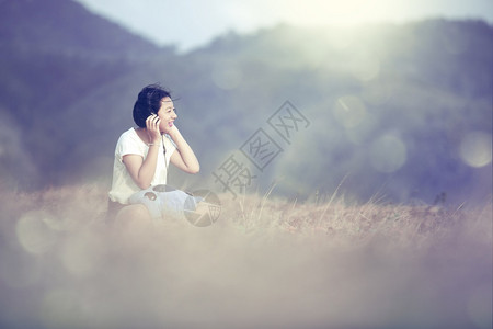 草吸引人的年轻青女孩在花园里用耳机听音乐在节日夏天听到音乐时笑着微的快乐和欢日本人图片