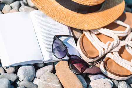 夏天稻草景观海滩概念草帽书太阳眼镜和在海滩上翻滚的沙帽子开着书上面有防晒霜和鞋图片