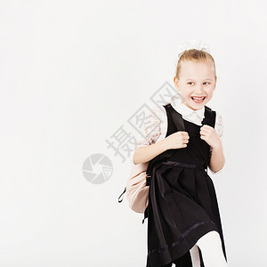 笑声的小女孩带着大背包跳跃和在白色背景下玩乐看着照相机回学校的概念小生有趣的图片