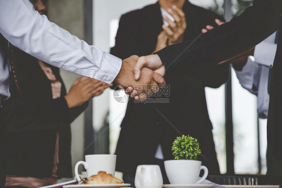 领导者商业伙伴与们握手一起向好心致爱者伸出双手在办公室外启动新项目握手团队合作伙伴关系现代城市背景的商人携手握团体公司的图片