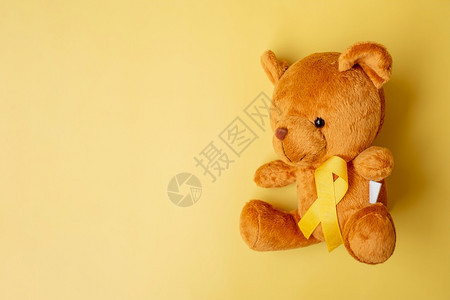黄色带熊娃的丝洋以黄色背景支持儿童生活和疾病9月儿童癌症意识和世界癌症日概念9月儿童癌症意识和世界癌症日概念国际的婴儿礼物图片