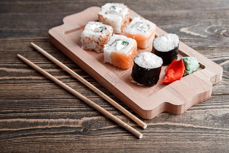 三种不同类的日本卷子上面有黄玉和姜在竹盘上放美丽的木制背景上竹盘鳗鱼牛油果不同的图片