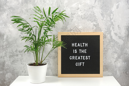 辅导健康是最好的礼物白色桌子上的信板励志名言和锅里绿色异国情调的棕榈花灰色石墙概念保健和医学当天的励志名言健康是最好的礼物白色桌图片