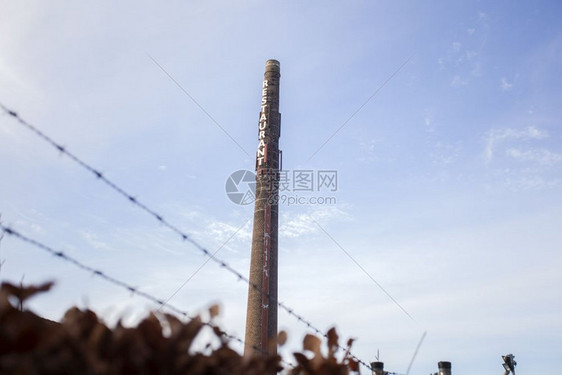 工业的老长砖烟囱上面写着餐厅对蓝天老工厂业用铁丝网旧长砖烟囱老工厂业河的图片