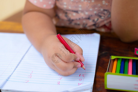 白人背景纸上的笔手写着英语文字的铅笔儿童学会写字母一个孩子用纸和蜡笔握着一根在他手上用来画笑声艺术家一种记事本图片