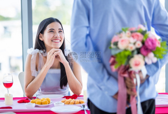 白种人展示超过结束一个男人的亚洲一个男拿着束玫瑰花手放在脸上的女人午餐后等待惊喜在餐厅背景中ChlooseofAsian图片