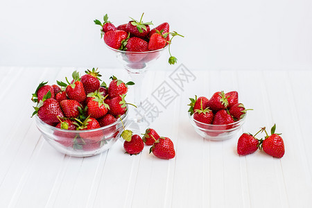 从你的花园收获健康地吃红成熟的草莓概念在你花园里用玻璃碗吃红成熟的草莓在你花园里用白木板桌子上摘取果实从你的花园里摘取绿色木制的图片