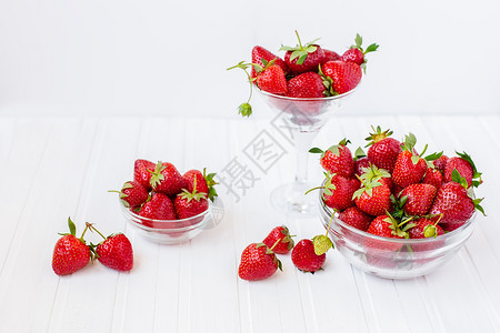 饮食从你的花园收获健康地吃红成熟的草莓概念在你花园里用玻璃碗吃红成熟的草莓在你花园里用白木板桌子上摘取果实从你的花园里摘取素食主图片