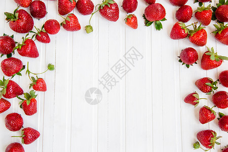 水果目的成熟红草莓散落在白色的木桌上背景有草莓文本的地方成熟红草莓散落在白色的木桌上背景有草莓团体图片