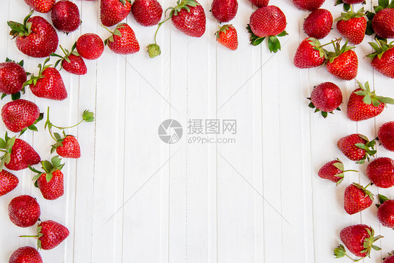 水果目的成熟红草莓散落在白色的木桌上背景有草莓文本的地方成熟红草莓散落在白色的木桌上背景有草莓团体图片