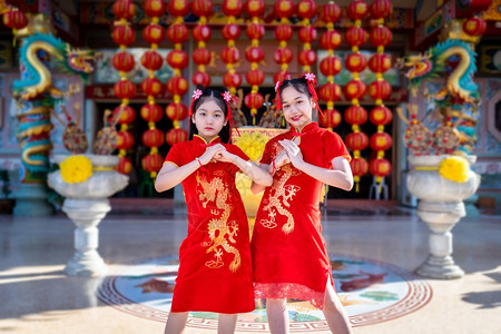 身着中华新年节国青春红传统香装饰的可爱小亚裔两个女孩长得漂亮美丽的笑脸乐趣服装礼物图片