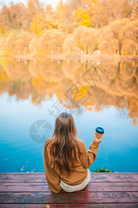 秋天有热外送咖啡室的可爱女孩在美丽的秋天户外靠近湖边可喜的小美少女爱树叶温暖图片