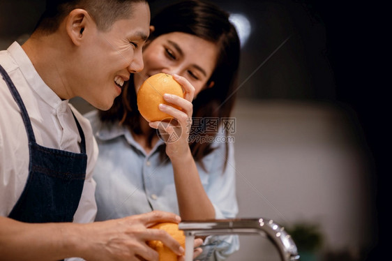 健康素食主义者男人厨房里的快乐年轻联谊会在厨房里打扫一些橙子准备在家一起烹饪的美味菜单图片