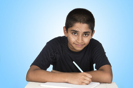 工作簿桌子一个英俊的印度孩子辛勤地做功课快乐的图片