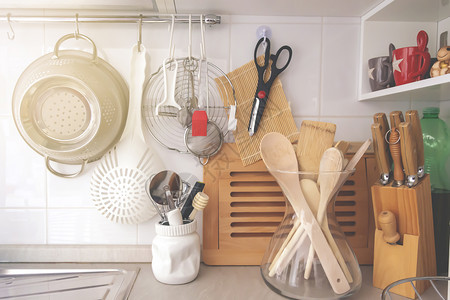白色的团体厨房角落有各种炊事用具包括一个玻璃容器中的椰子刀和木用具滤器图片