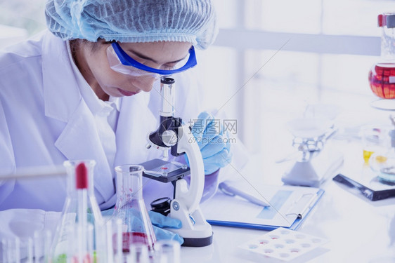 女科学家使用显微镜进行化学研究图片