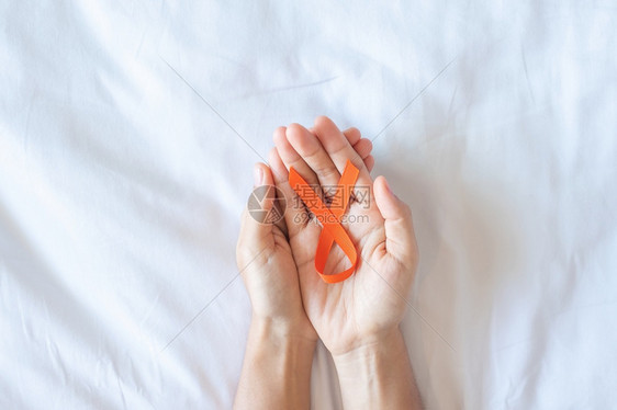 手拿橙色丝带预防癌症概念图片
