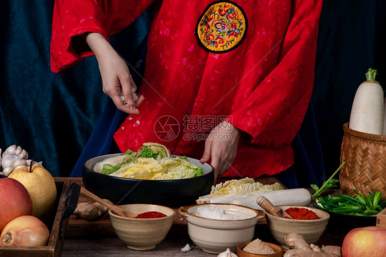 厨房这样的萝卜身穿韩国传统服装汉博克的亚裔妇女手工撒盐并配有大蒜高清朝鲜辣椒新蔬菜等成分的Kimchi成份图片