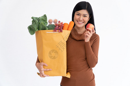 快乐的亚洲妇女笑着拿苹果带一个购物纸袋在从杂货店来的快递员家里送货后超市为新生活方式提供超市商品的概念女抓住微笑图片