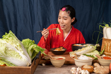韩国人身穿传统服装的亚洲妇女汉博克正在混合新鲜搅拌机和基姆奇成分配有盐大蒜高清菜新鲜蔬等成分新鲜的餐厅图片