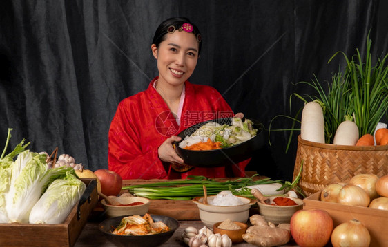 女腌制身穿韩国传统服装的亚洲妇女汉博克正在混合新鲜搅拌机和基姆奇成分配有盐大蒜高清菜新鲜蔬等成分手图片