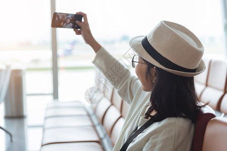 微笑的年轻亚洲女旅行者在国际机场度假旅行时使用手机或智能自拍和并前往场旅行互联网亚洲人自由图片