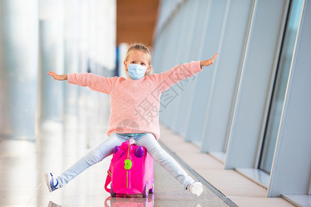 假期闲暇乘客小可爱的带着外科面具的小孩在国际机场面对保护在机场等待登的小孩在场等待登图片
