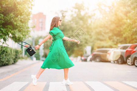 年轻的华丽在大城市周围走动的年轻女子穿着绿裙的漂亮女孩肖像在城市散步的绿色衣服年轻女子首都图片