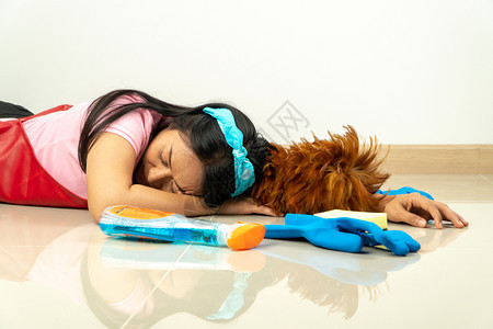 家庭主妇因疲劳而躺在散落各种清洁设备的地上图片