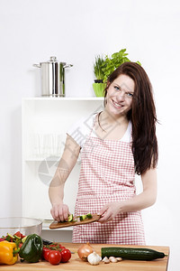 女人加黄瓜在厨房的美人沙拉上加黄瓜厨房的开心女人加切黄瓜烹饪食物女图片