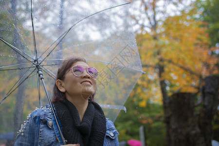 以秋色叶子站着雨伞的女游客笑脸在日本北海道hodakaidojapan是最受欢迎的秋季旅游目地美丽随意颜色图片