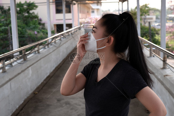 舷梯感染安全一名黑人衬衫女站在穿戴呼吸器N95防毒面具的黑衬衫女面前以保护免受空气呼吸道疾病的影响因为甲型流感在路上染布满了本底图片