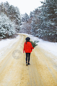 一个穿着红色毛衣和帽子的女孩站在雪道中间松枝的森林里周末旅行穿着红色毛衣和帽子的女孩站在雪道中间松枝的森林里周末旅行快乐的幸福微图片