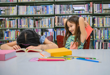 文学有两个可爱的快乐和多样化女孩在阅读书玩耍来打在学校图书馆的睡友有趣是人们生活方式以及教育友谊儿童与团体活动休闲知识孩子图片
