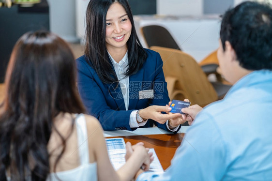 亚洲女销售员在展厅信用卡模型签署购买合同后决定新车时从夫妇客户那里收回信用卡的亚洲销售员退款男人手商业图片