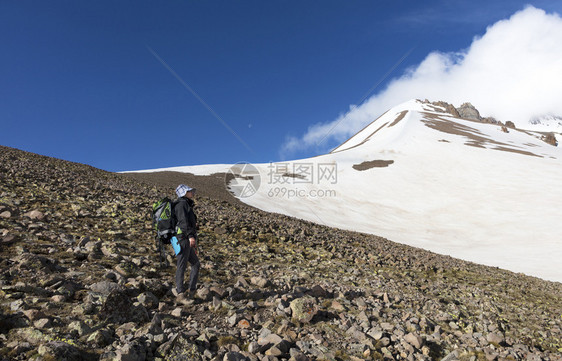 带着背包的女游客去雪山上旅行游者从山坡上爬到雪盖顶端天男人探险家图片