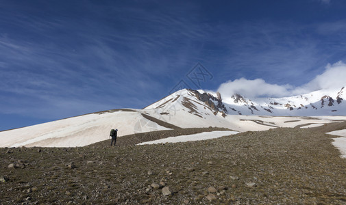 积极的一种登山者带着背包的女游客去雪山上旅行游者从山坡上爬到雪盖顶端图片