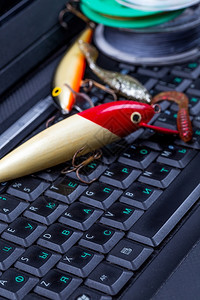 钓鱼工具线诱饵黑键盘上的游泳诱饵笔记本准备钓鱼旅行在线购物论坛一种夹具蛴螬背景图片