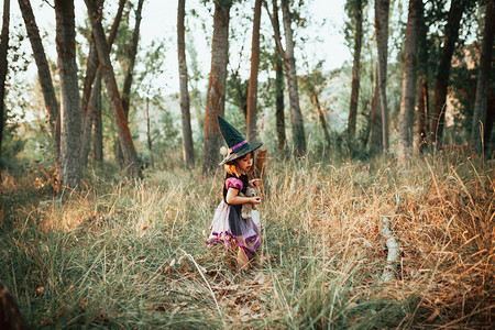 女孩在万圣节期间树林里伪装成庆祝帽子魔术师图片