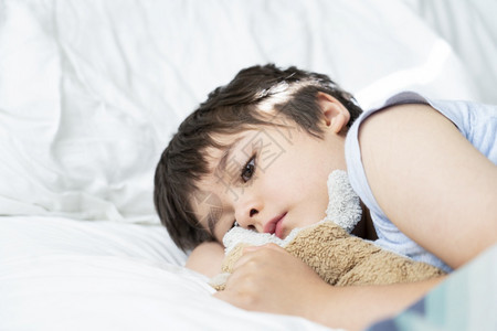 健康7岁躺在床上的小孩睡梦中子清晨醒来时用早光在卧室里醒来可爱的小男孩和狗玩具睡在床上儿童保健护理或幼儿睡眠问题年轻的老图片