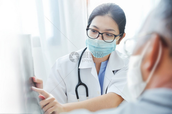 疾病Covid19或Corona亚洲女医生戴眼镜和外科面具在医院的门诊室向老年病人提供咨询在Covid19或Corona期间医生图片