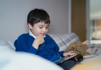 房间乐趣Kid使用互联网向老师发送家庭作业坐在沙发上的孩子放学后独自客厅休息下课后单独坐沙发上放松一下的孩子们校友触碰图片