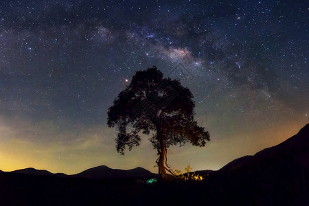 银河系与宇宙中的星和太空尘埃夜上的黄道带光在山景上的树云移动PhuSawan水库Phetchaburi山景泰国自然天文学图片