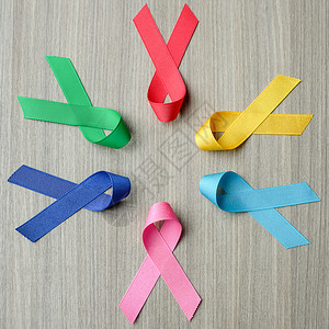 丝带2月4日世界癌症2月4以木制背景为蓝红绿粉色和黄颜的彩带支持人们生活和疾病保健医药概念十月为了图片